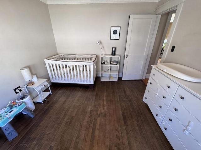 bedroom featuring a crib and dark wood-style floors