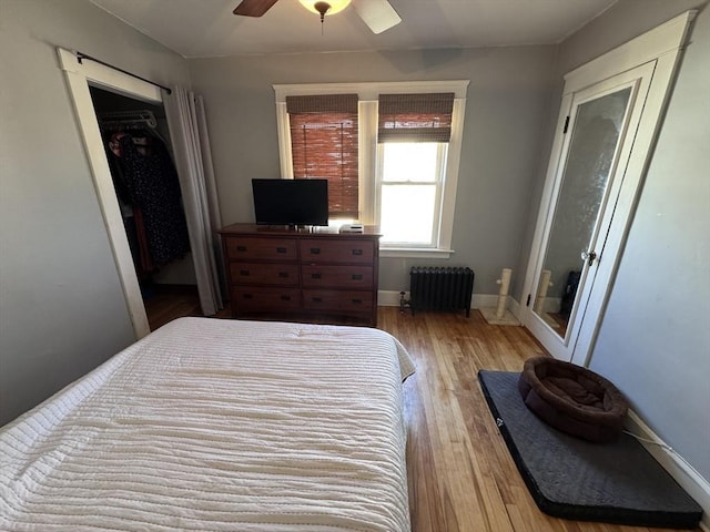 bedroom featuring a ceiling fan, radiator heating unit, wood finished floors, and baseboards