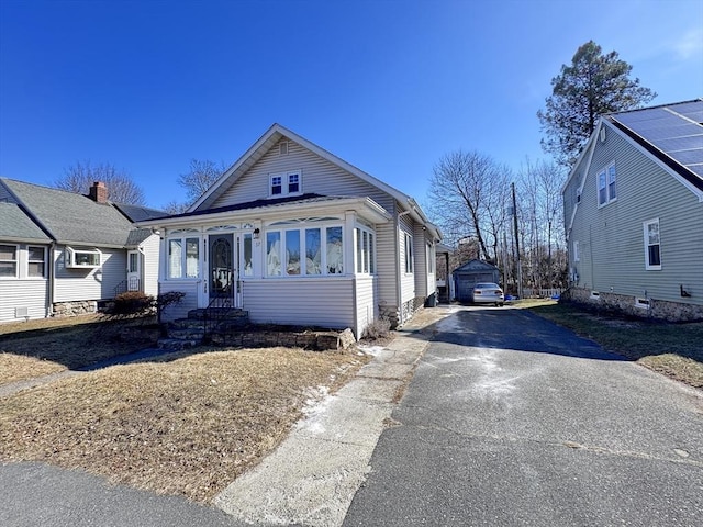 bungalow-style home featuring aphalt driveway and an outbuilding