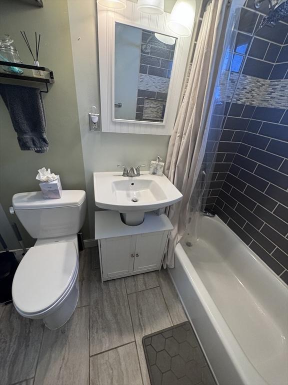 bathroom with vanity, toilet, shower / tub combo with curtain, and wood tiled floor