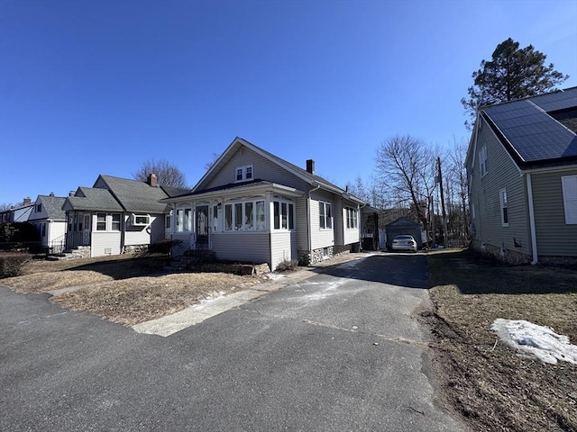 exterior space with a chimney, an outdoor structure, and driveway