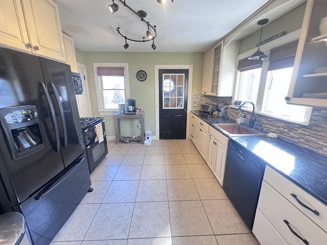 kitchen featuring glass insert cabinets, decorative backsplash, light tile patterned flooring, black appliances, and a sink