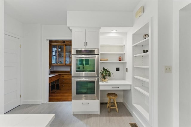 18 Alden St, Newton, MA 02459 - kitchen featuring stainless steel double oven, white cabinetry, light wood-type flooring, open shelves, and light countertops