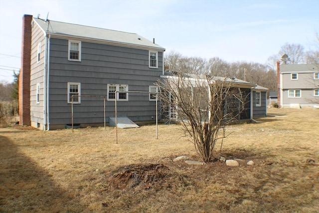 rear view of property featuring a lawn and a chimney