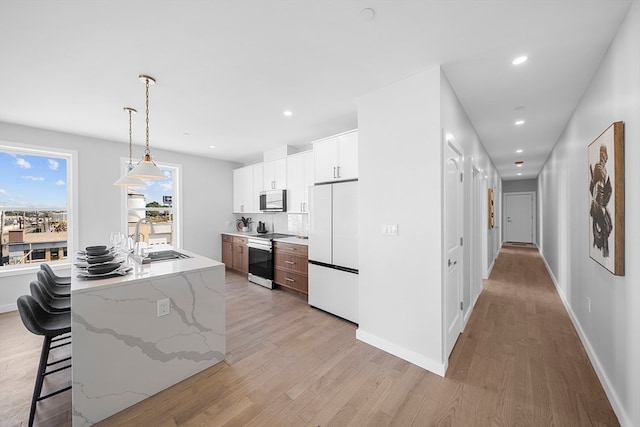 kitchen with white cabinets, range with electric cooktop, sink, white fridge, and light stone counters