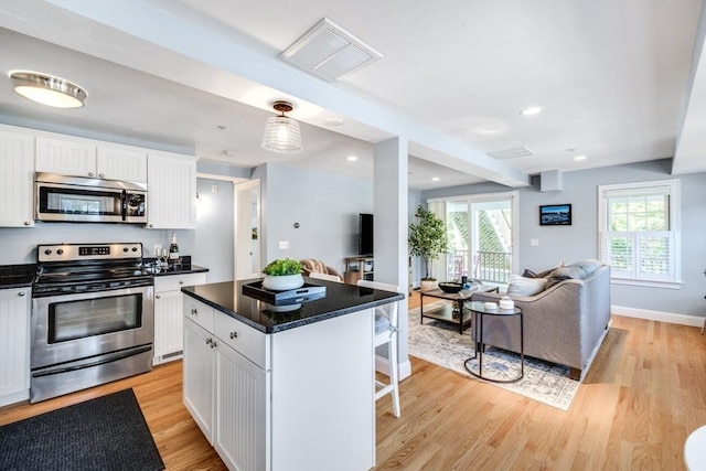 606 W Falmouth Hwy Unit 7, Falmouth, MA 02540 - kitchen featuring visible vents, a kitchen bar, appliances with stainless steel finishes, open floor plan, and white cabinetry