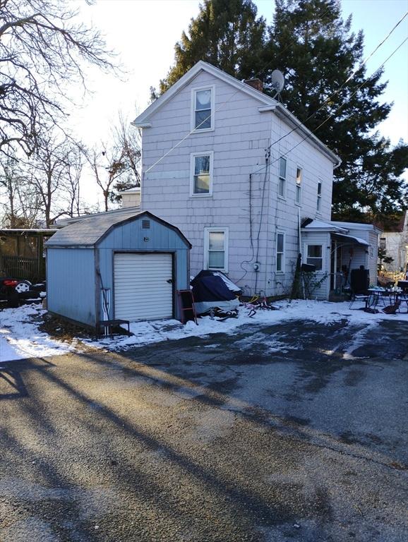 snow covered property featuring an outdoor structure and a garage