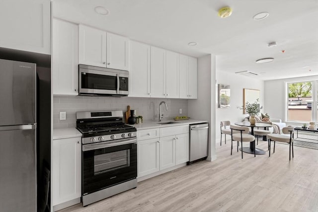 602 Canterbury Unit 5, Boston, MA 02131 - kitchen featuring stainless steel appliances, light countertops, light wood-style floors, backsplash, and white cabinetry