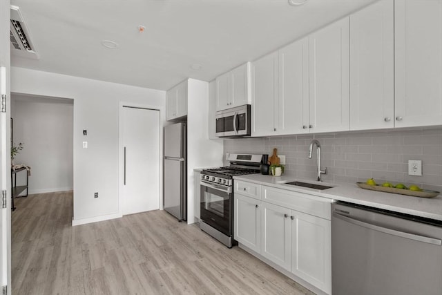602 Canterbury Unit 5, Boston, MA 02131 - kitchen featuring stainless steel appliances, light wood-type flooring, tasteful backsplash, and white cabinets