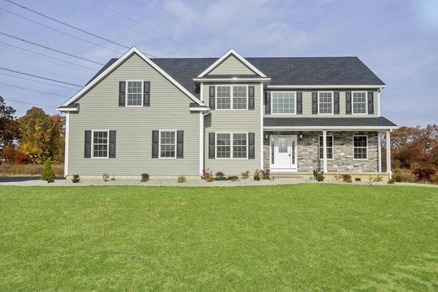 view of front of house featuring a shingled roof, a front lawn, and stone siding