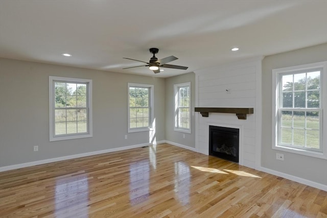 unfurnished living room with light wood-style floors, baseboards, a fireplace, and a ceiling fan