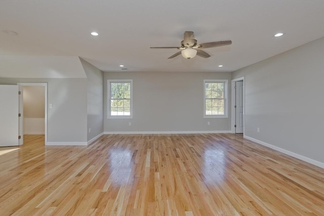 empty room with a ceiling fan, baseboards, plenty of natural light, and light wood-style flooring