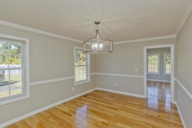 unfurnished dining area featuring crown molding, a notable chandelier, plenty of natural light, and light wood-type flooring