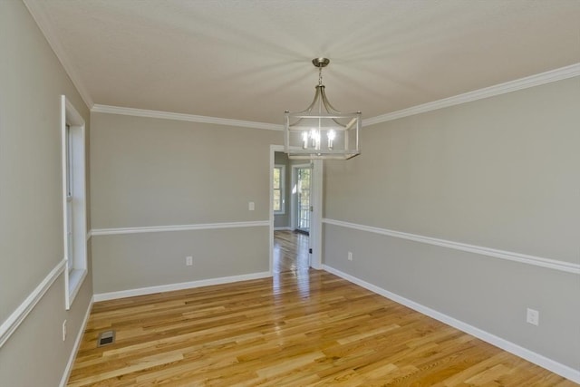 spare room featuring baseboards, an inviting chandelier, ornamental molding, and light wood finished floors