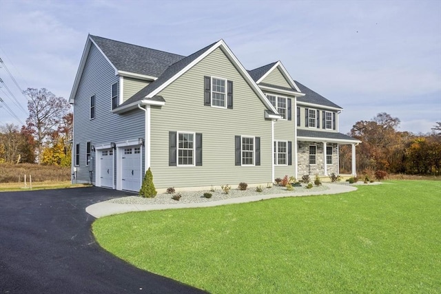 rear view of house featuring a lawn, driveway, and a garage
