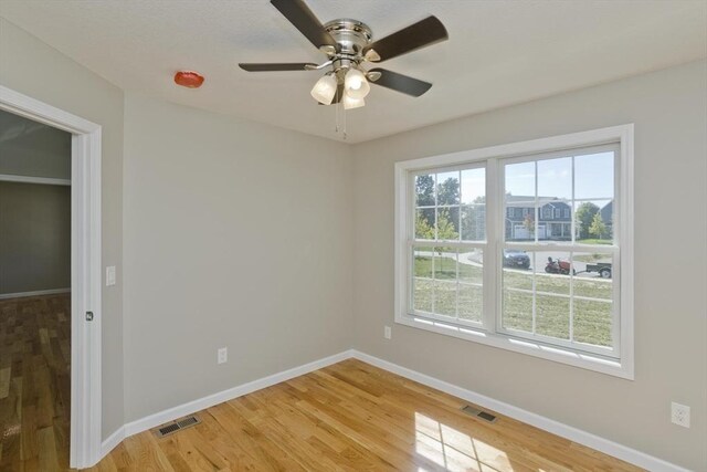 spare room with a ceiling fan, baseboards, visible vents, and light wood finished floors