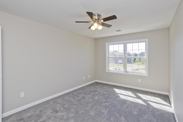 carpeted empty room featuring baseboards, visible vents, and ceiling fan