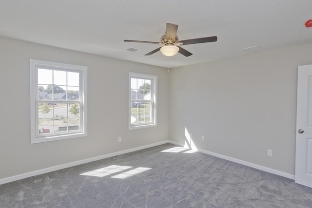 carpeted empty room featuring visible vents, a ceiling fan, and baseboards