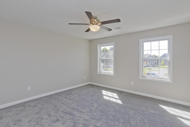 empty room with baseboards, ceiling fan, carpet flooring, and visible vents