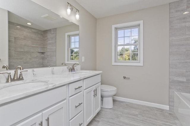 full bath featuring baseboards, a sink, walk in shower, and double vanity
