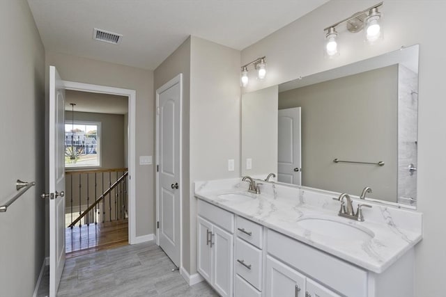full bath featuring a sink, double vanity, wood finished floors, and visible vents