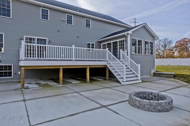 rear view of property featuring a wooden deck, a sunroom, stairs, a patio area, and an outdoor fire pit