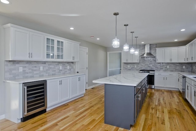 kitchen with wall chimney range hood, white cabinets, beverage cooler, stainless steel appliances, and decorative backsplash