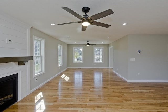 unfurnished living room with ceiling fan, a large fireplace, light wood-style flooring, recessed lighting, and baseboards