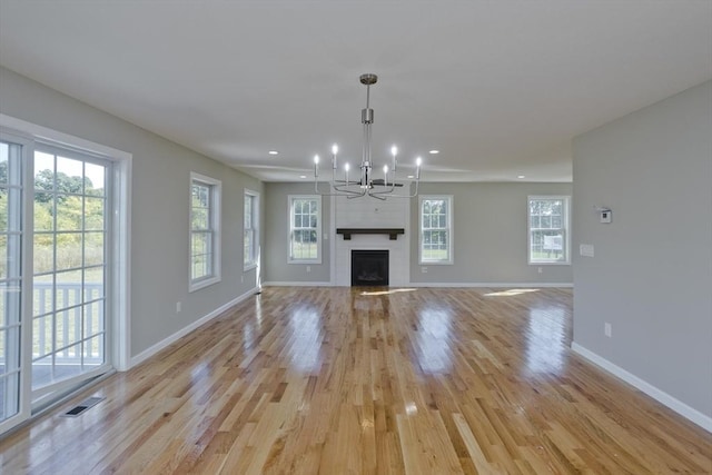 unfurnished living room with visible vents, light wood finished floors, baseboards, and an inviting chandelier