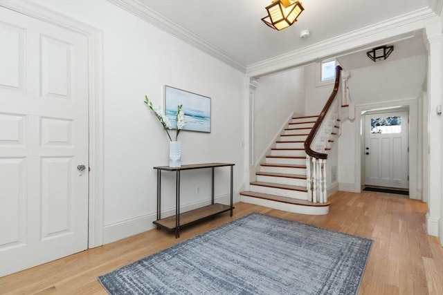 entryway with crown molding, decorative columns, stairway, wood finished floors, and baseboards