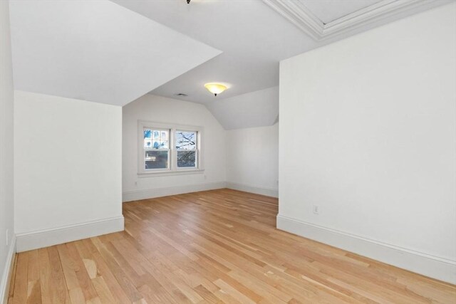 bonus room featuring light wood-style flooring, baseboards, and vaulted ceiling