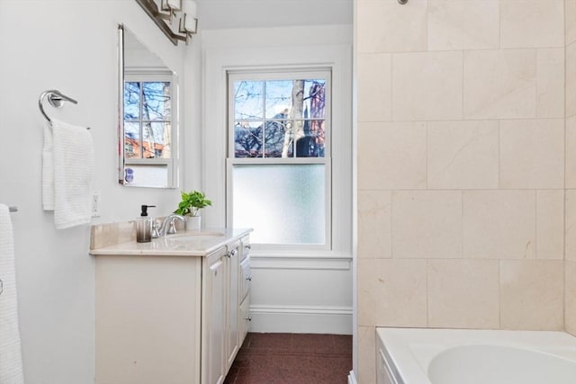 full bath with vanity, a bathtub, and baseboards