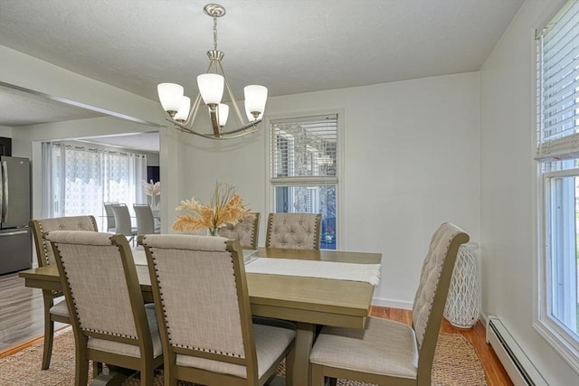 13 Woodland Dr, Hudson, MA 01749 - dining area with a baseboard radiator, a chandelier, wood finished floors, plenty of natural light, and a textured ceiling