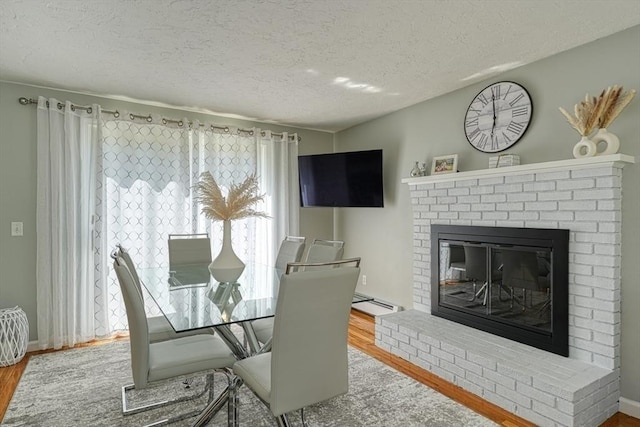 13 Woodland Dr, Hudson, MA 01749 - dining space with wood finished floors, a textured ceiling, and a fireplace
