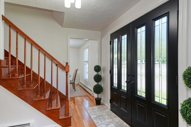 13 Woodland Dr, Hudson, MA 01749 - foyer with a baseboard radiator, light wood-type flooring, stairs, a textured ceiling, and french doors