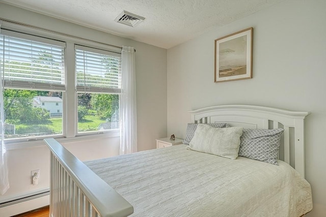 13 Woodland Dr, Hudson, MA 01749 - bedroom featuring a baseboard heating unit and a textured ceiling