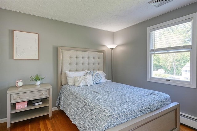 13 Woodland Dr, Hudson, MA 01749 - bedroom with a baseboard heating unit, multiple windows, wood finished floors, a textured ceiling, and baseboards