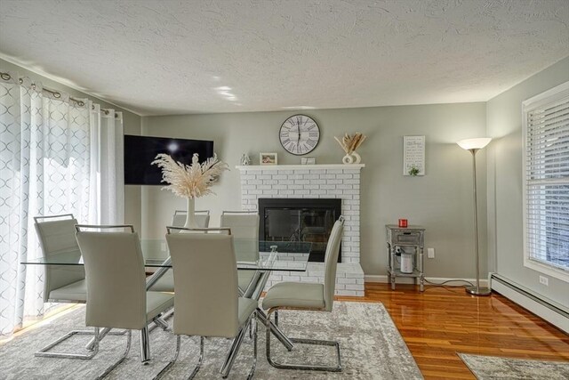 13 Woodland Dr, Hudson, MA 01749 - dining area featuring a textured ceiling, wood finished floors, baseboard heating, a fireplace, and baseboards