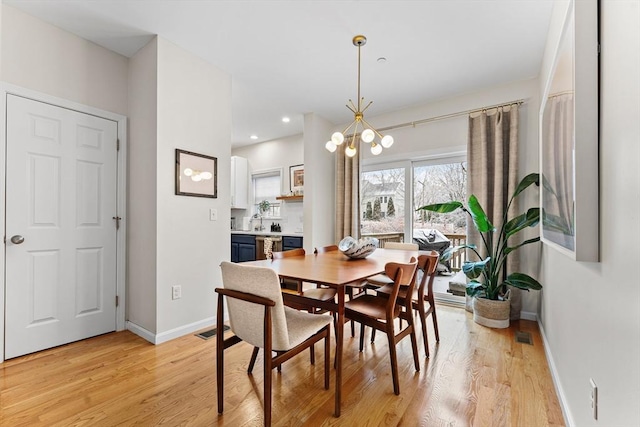 dining space featuring sink, light hardwood / wood-style floors, and a notable chandelier