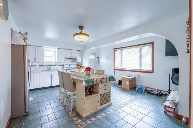 12 Charles St, Brockton, MA 02301 - kitchen with white range, arched walkways, freestanding refrigerator, a sink, and light countertops