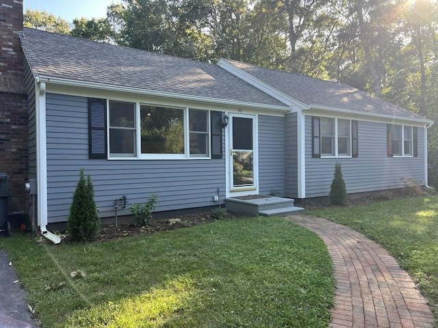 single story home featuring a shingled roof and a front yard