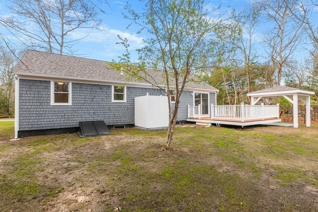 back of house with roof with shingles, a wooden deck, and a yard