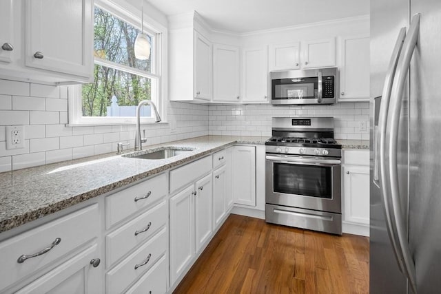kitchen featuring dark wood-style flooring, a sink, stainless steel appliances, white cabinetry, and backsplash