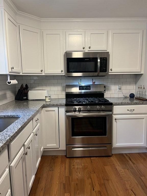 kitchen with white cabinets, appliances with stainless steel finishes, decorative backsplash, and dark wood finished floors