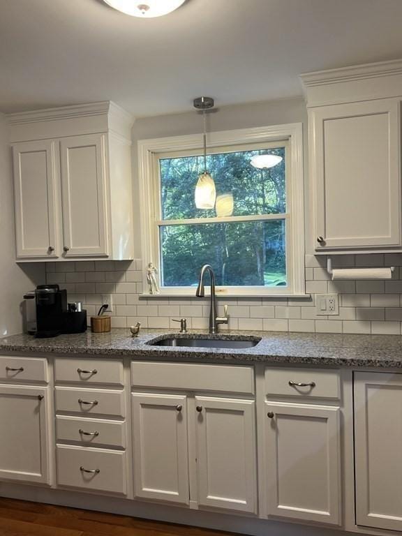 kitchen with stone countertops, a sink, white cabinetry, and decorative backsplash