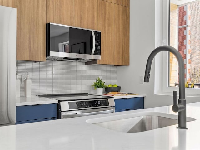 kitchen featuring a sink, stainless steel appliances, modern cabinets, light countertops, and decorative backsplash