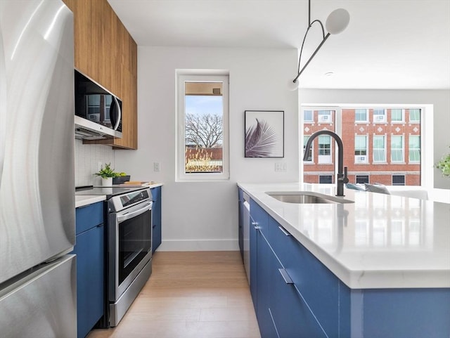kitchen with a sink, stainless steel appliances, blue cabinetry, and modern cabinets