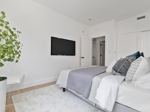 bedroom with baseboards, a closet, visible vents, and wood finished floors