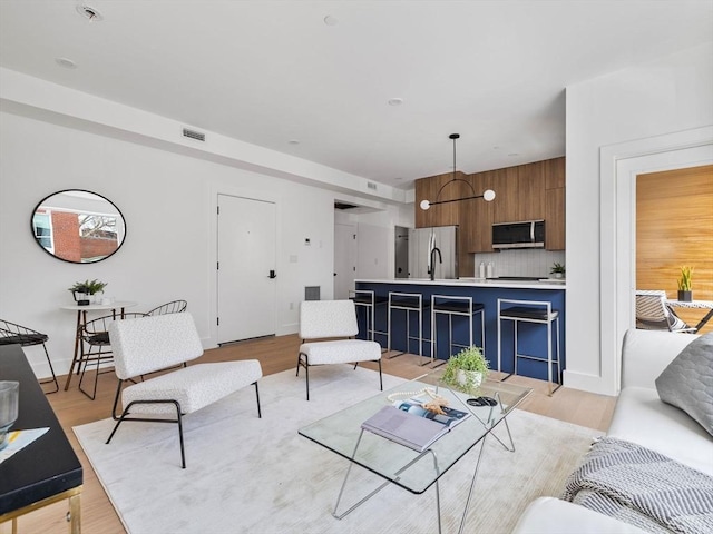 living area featuring light wood finished floors and visible vents