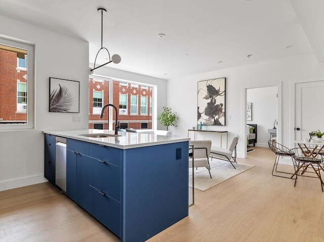 kitchen with light countertops, light wood-style flooring, blue cabinetry, and a sink